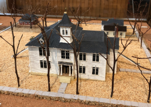 Small model of a Louisville Grade School, a white two story building with a bell tower