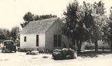 Historic photo of a white home surrounded by tall trees