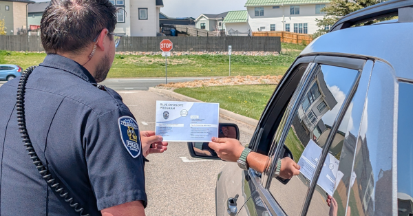 Officer Receiving Blue Envelope From Driver 