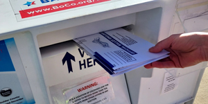 Hand placing ballot into ballot drop box